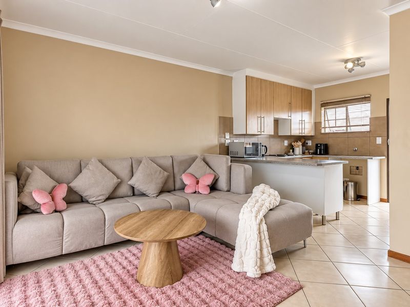 Open-plan living area featuring a functional kitchen with built-in cabinetry, granite countertops, and tiled flooring, seamlessly connected to the lounge space.