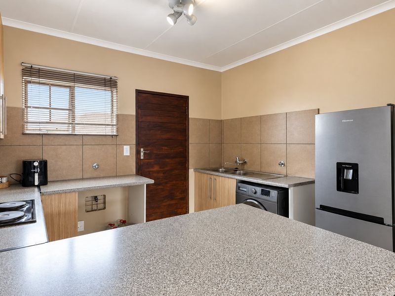 A functional kitchen featuring laminate countertops, tiled backsplash, built-in cabinetry, and dedicated plumbing for a washing machine.