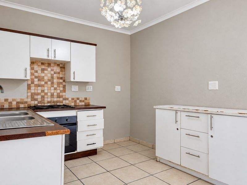 A functional kitchen featuring white cabinetry, a tiled backsplash, built-in oven and hob, and tiled flooring, offering a clean and practical workspace.