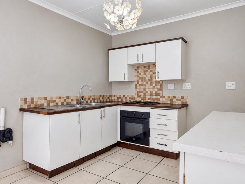 A functional kitchen featuring white cabinetry, a built-in oven with gas hob, tiled backsplash, and tiled flooring, ready for personalization.