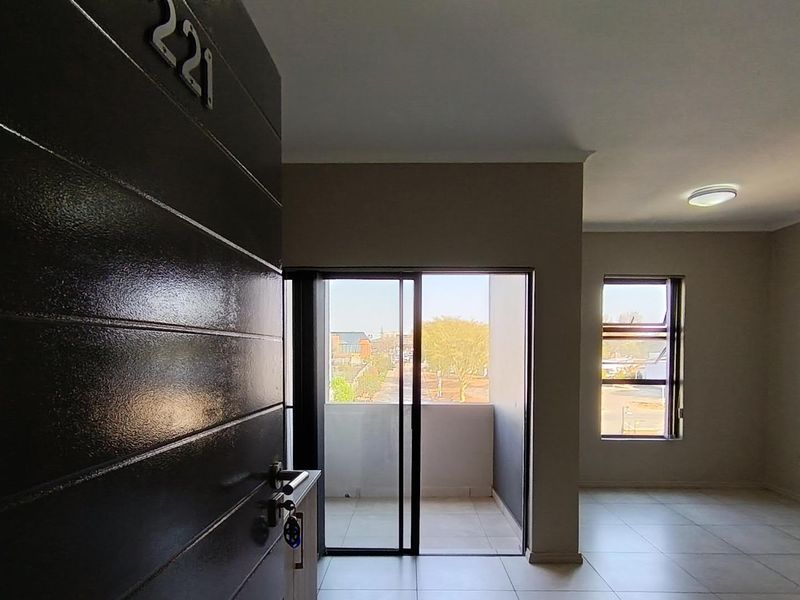 Entrance area of an apartment featuring tiled flooring, a sliding glass door leading to a balcony, and neutral wall finishes.