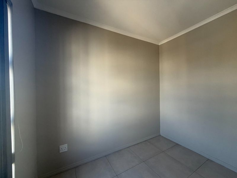 A clean, empty bedroom featuring neutral painted walls, tiled flooring, and modern skirting boards, providing a blank canvas for interior design.