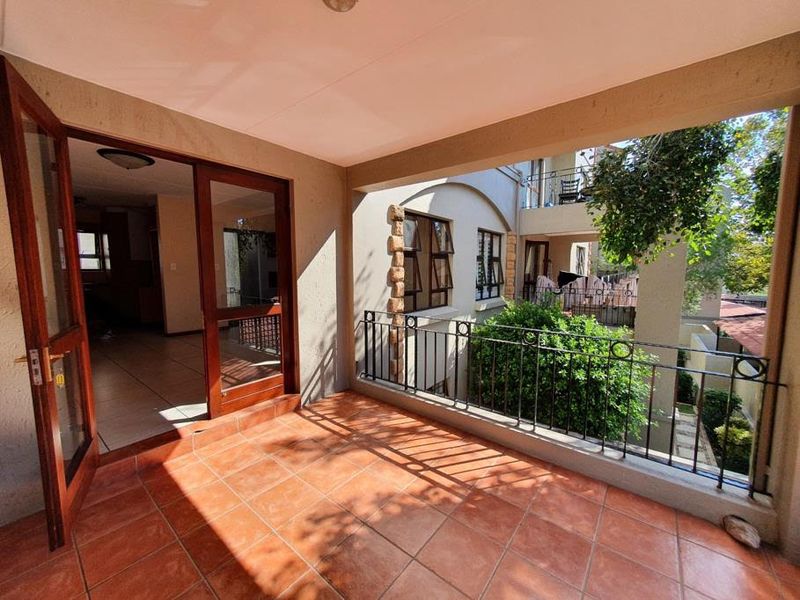 A covered balcony featuring terracotta-style tiled flooring and a wrought iron balustrade, providing an outdoor extension to the interior living space.