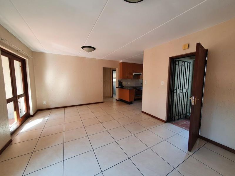 Open plan living area featuring tiled flooring, direct access to a balcony, and a functional kitchen with built-in cabinetry and an extractor fan.