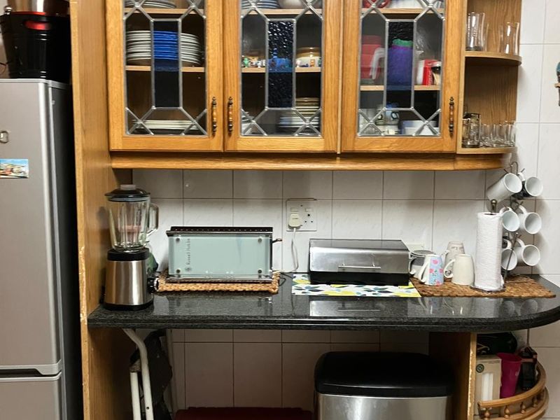 A kitchen area featuring traditional wooden cabinetry with leaded glass inserts, granite countertops, and a tiled backsplash, offering functional storage and workspace.