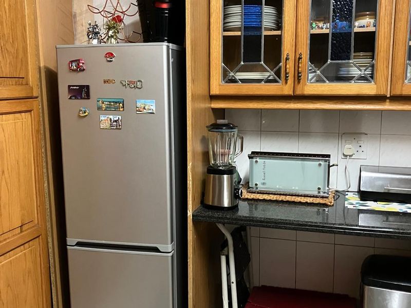A kitchen corner featuring traditional wooden cabinetry with leaded glass inserts, granite countertops, and tiled backsplash, offering a classic aesthetic.
