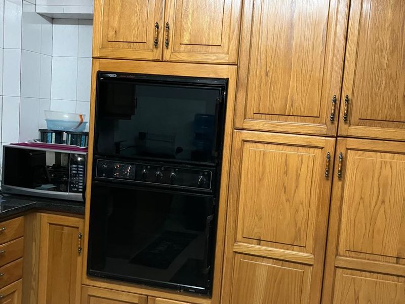 Kitchen featuring traditional wooden cabinetry and a built-in double oven with tiled flooring and backsplash.