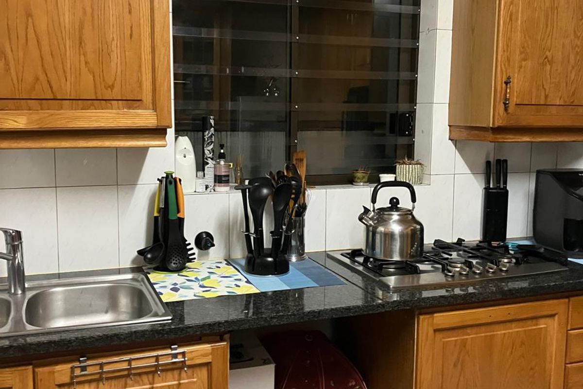 A functional kitchen featuring traditional wooden cabinetry, granite countertops, a gas hob, and a tiled backsplash with a window overlooking the exterior.