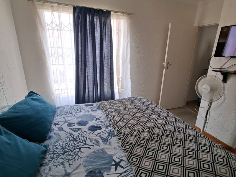 A compact bedroom featuring a window with a security gate, textured walls, and standard internal door access.