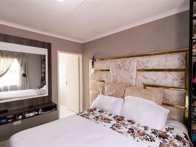 A bedroom featuring a decorative marble-effect headboard, a wall-mounted mirror with an integrated floating shelf, and neutral wall finishes.