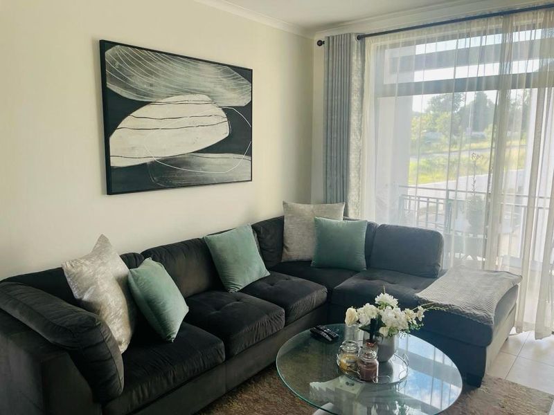 A bright and comfortable living room featuring tiled flooring and a large sliding glass door that provides access to the balcony.