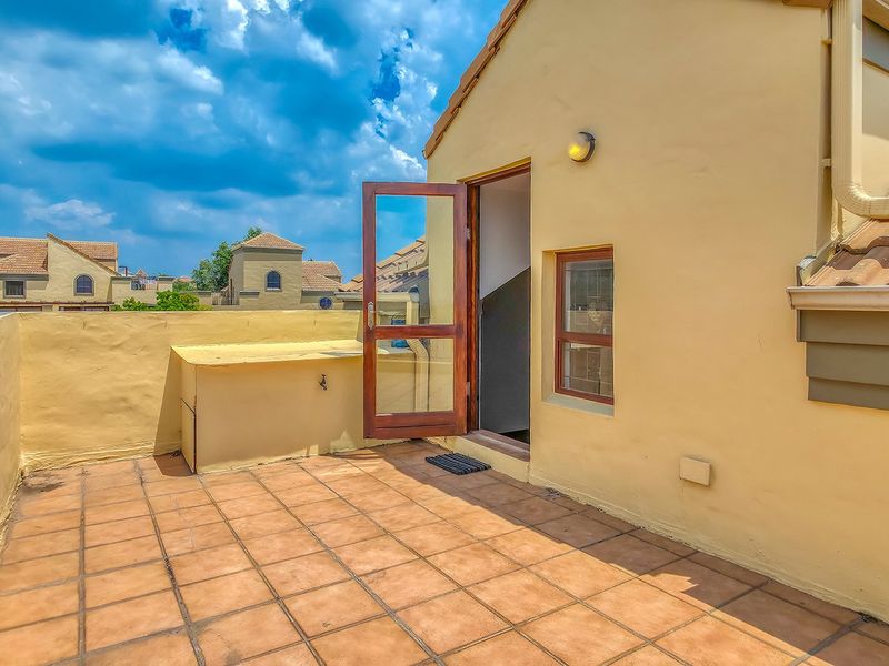A private rooftop balcony featuring tiled flooring, an external water tap, and direct access to the interior through a timber door.