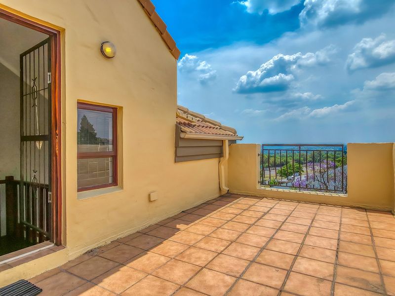 Spacious open-air balcony featuring tiled flooring, a wrought iron balustrade, and scenic elevated views, perfect for outdoor relaxation.