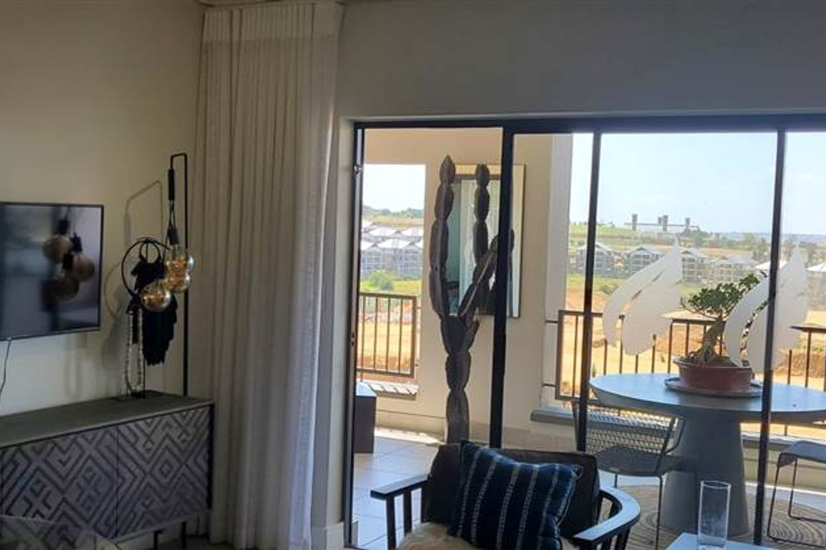 A bright living room featuring large sliding glass doors that open onto a balcony, providing natural light and views of the surrounding area.