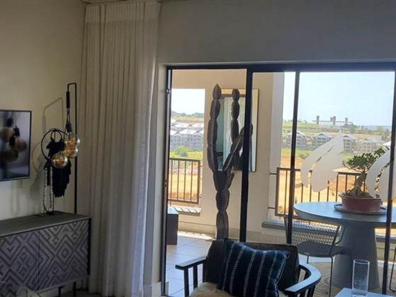 A bright living room featuring large sliding glass doors that open onto a balcony, providing natural light and views of the surrounding area.