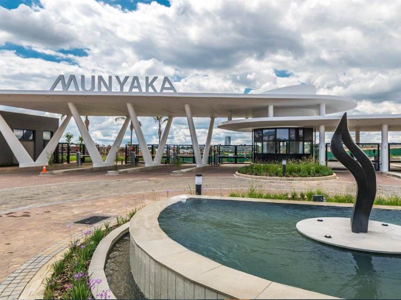 Modern security entrance gatehouse for Munyaka estate featuring a contemporary architectural canopy, paved driveway, and a central water feature.