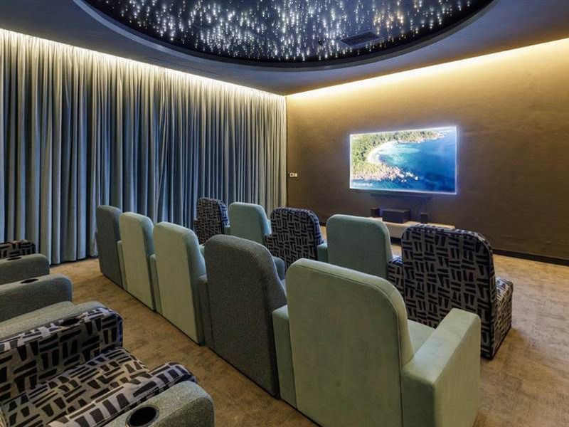 A luxury private cinema room featuring a recessed star-effect ceiling, ambient cove lighting, and full-height acoustic curtains for an immersive viewing experience.