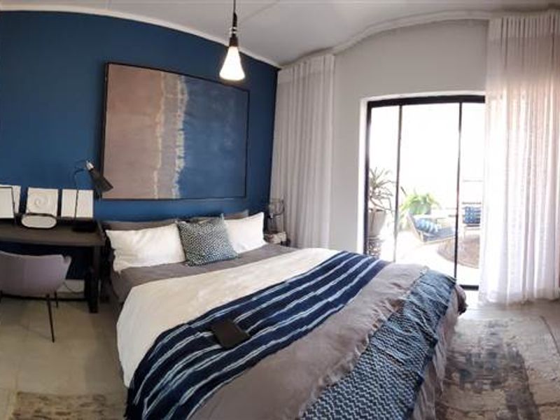 A well-maintained bedroom featuring built-in cupboards, tiled flooring, and a sliding glass door providing access to an outdoor area.