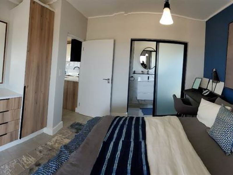 Modern bedroom featuring built-in wooden cabinetry, a feature wall, and direct access to an en-suite bathroom.