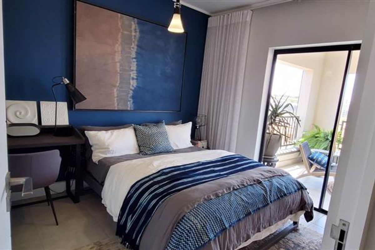 A well-lit bedroom featuring tiled flooring and a sliding glass door providing direct access to an outdoor balcony area.