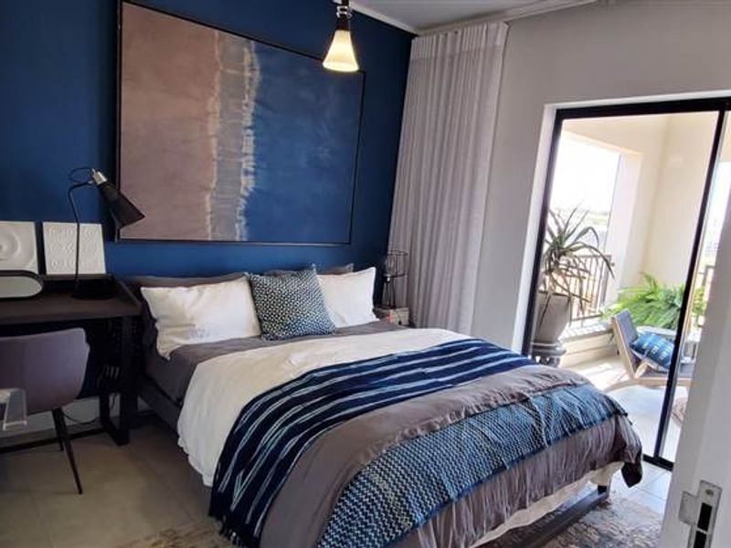 A well-lit bedroom featuring tiled flooring and a sliding glass door providing direct access to an outdoor balcony area.