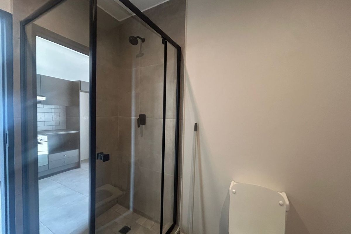 Modern bathroom featuring a walk-in shower with a black-framed glass enclosure and a standard toilet.