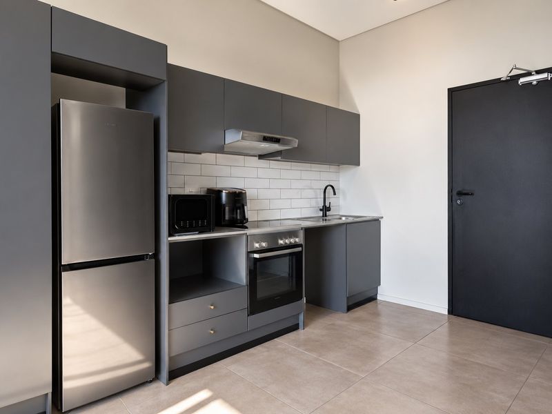 Modern kitchen featuring sleek grey cabinetry, subway tile backsplash, integrated oven, extractor fan, and high-quality tiled flooring.
