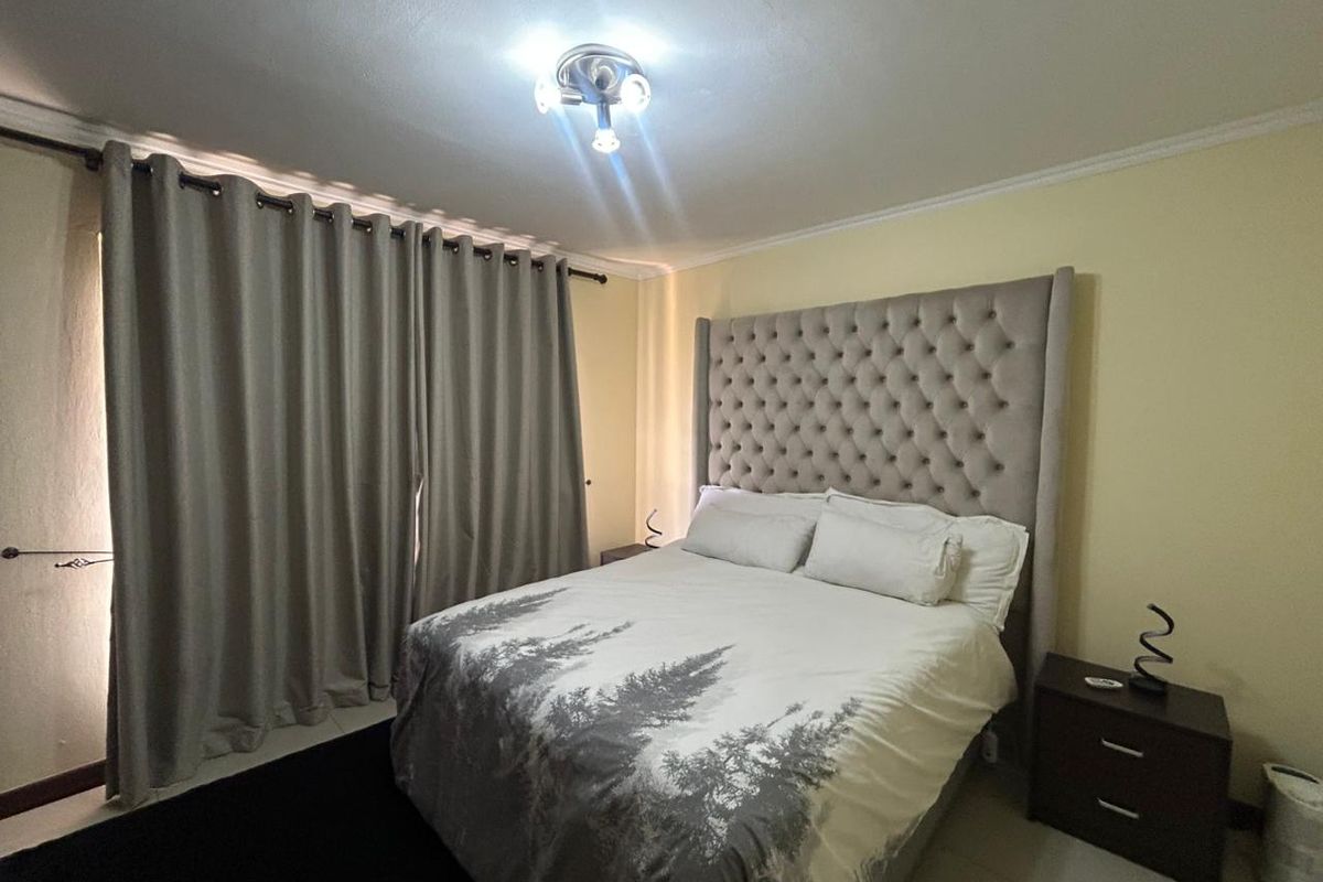 A bedroom featuring tiled flooring, a central ceiling light fixture, and floor-to-ceiling curtains.