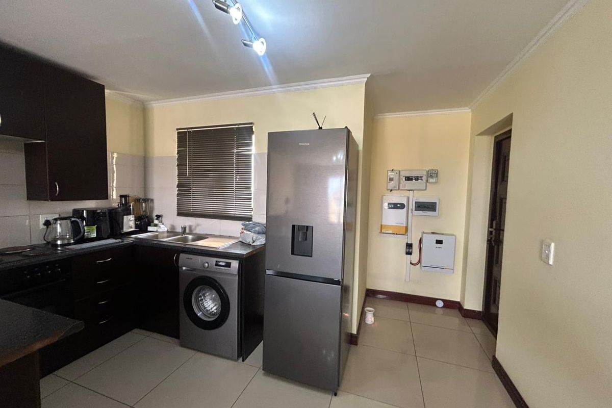 Functional kitchen featuring dark cabinetry, tiled flooring, and an integrated solar power inverter system mounted on the wall.