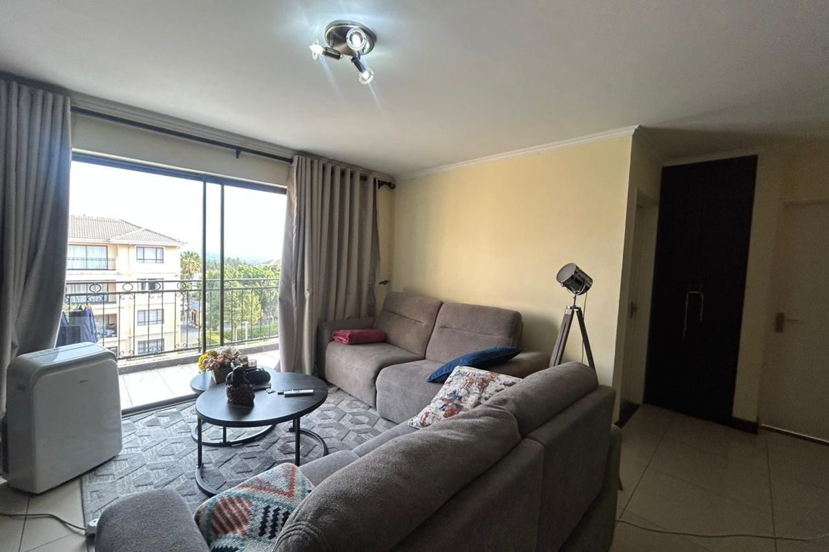 A living room featuring tiled flooring, a ceiling light fixture, and a large sliding glass door providing access to a balcony with exterior views.
