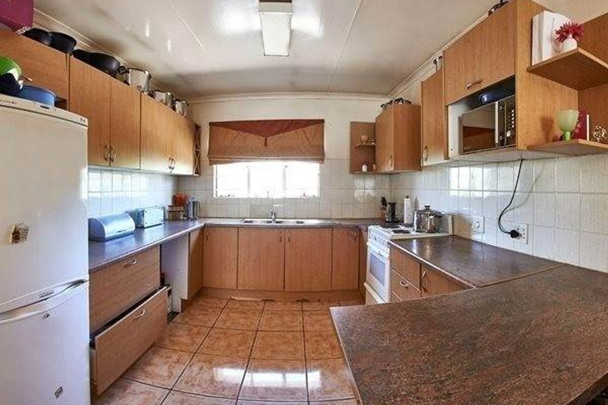 A functional kitchen featuring laminate cabinetry, tiled backsplash, and tiled flooring, offering a practical layout with built-in cooking appliances and ample counter space.