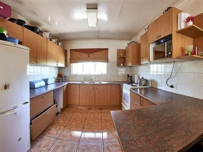 A functional kitchen featuring laminate cabinetry, tiled backsplash, and tiled flooring, offering a practical layout with built-in cooking appliances and ample counter space.