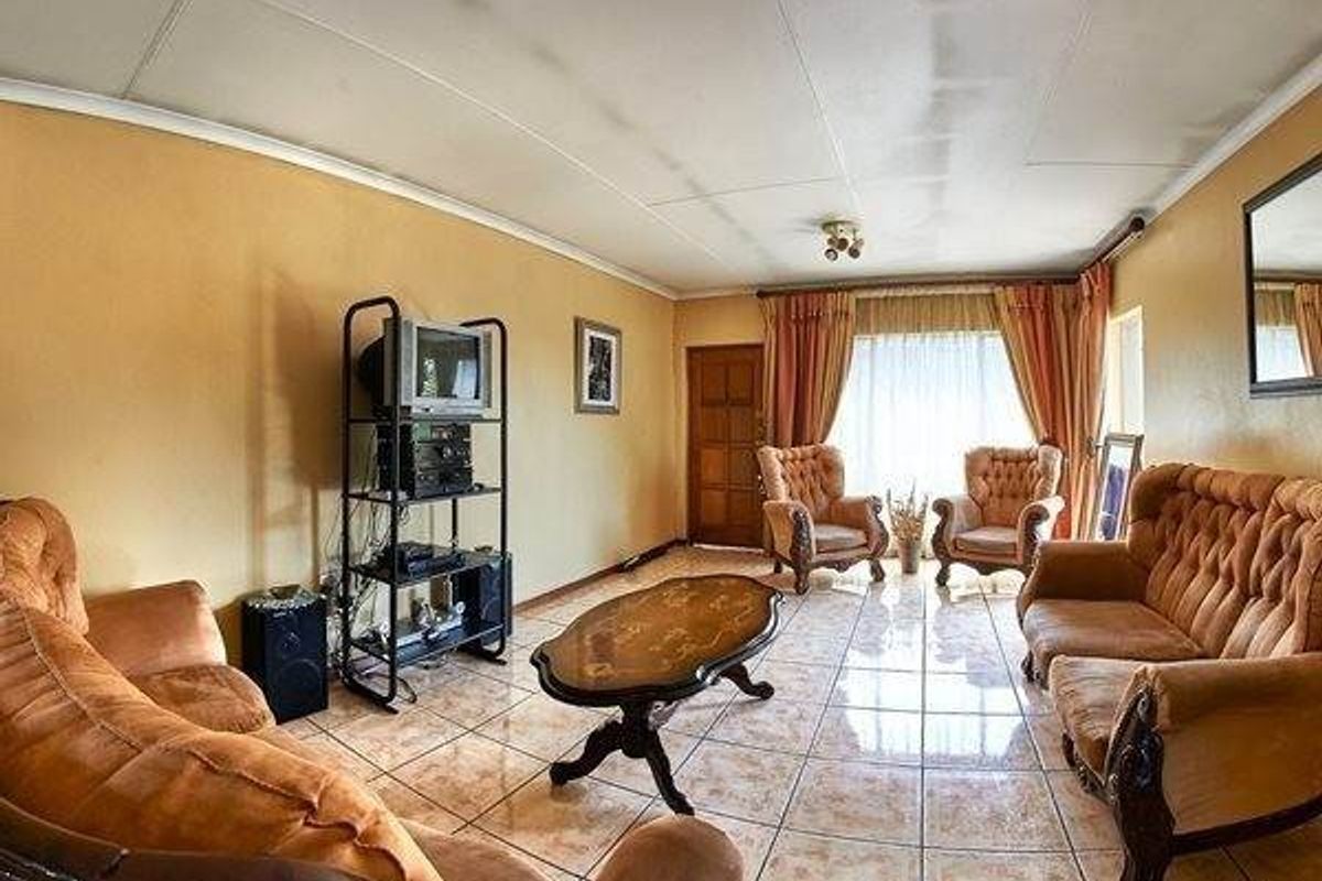 A dated living room featuring tiled flooring and ceiling panels, offering a spacious layout ready for modern updates and renovation.