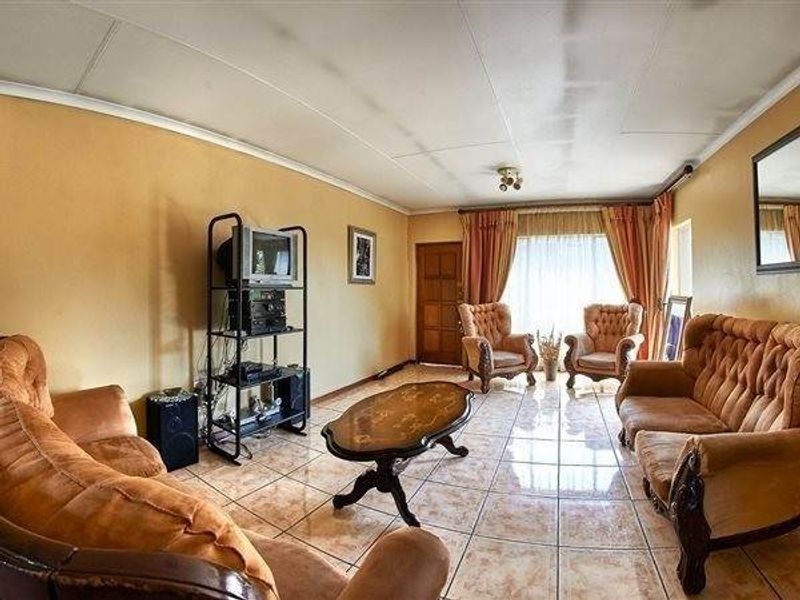 A dated living room featuring tiled flooring and ceiling panels, offering a spacious layout ready for modern updates and renovation.
