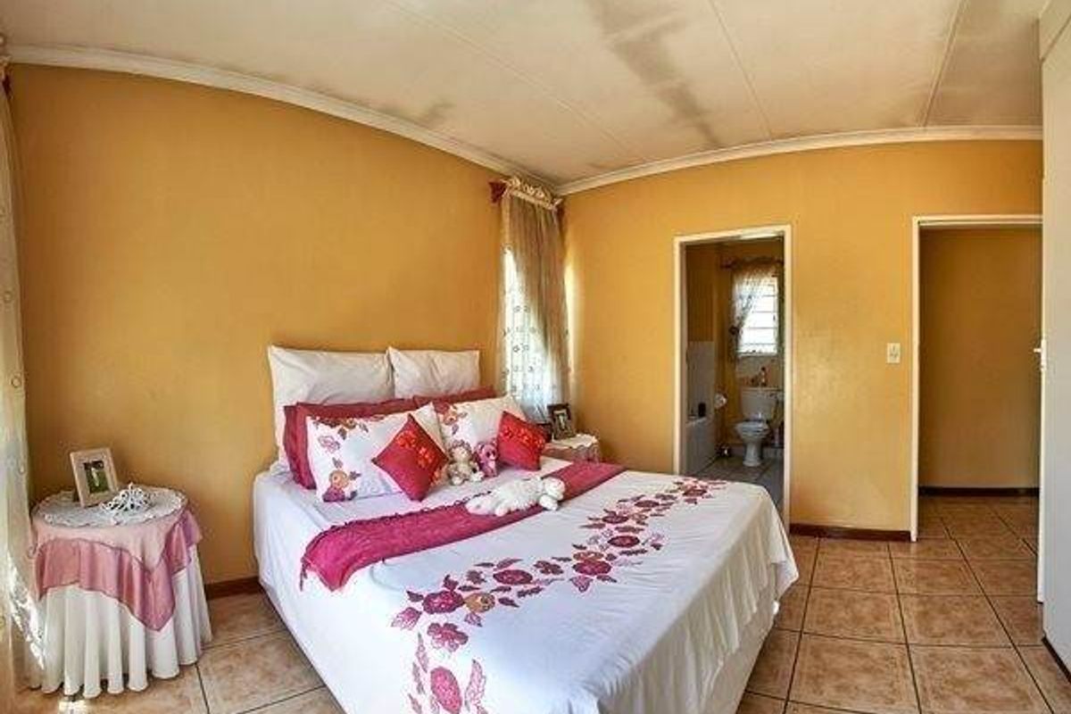 Bedroom featuring tiled flooring and direct access to an en-suite bathroom, with visible signs of ceiling water damage requiring maintenance.