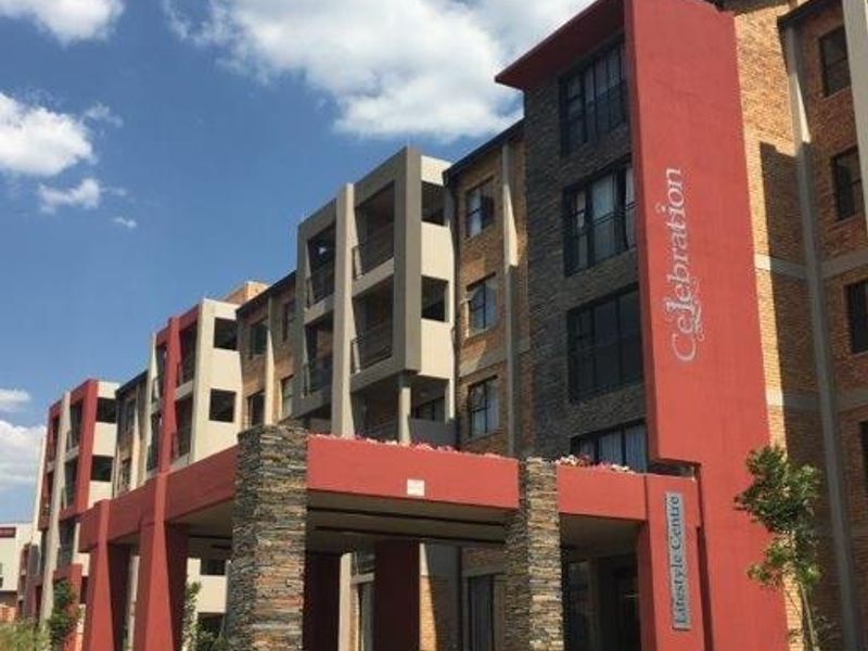 Front elevation of the Celebration Lifestyle Centre apartment complex, featuring modern architectural design with stone cladding and a covered entrance portico.