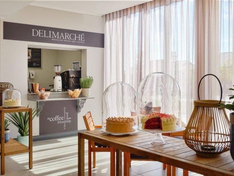 A bright clubhouse area featuring a serving hatch, tiled flooring, and large windows with sheer curtains, suitable for communal dining or social gatherings.
