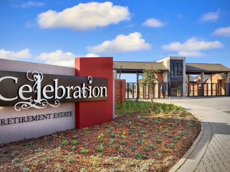 The entrance to Celebration Retirement Estate featuring a modern security gate, paved driveway, and landscaped garden area.