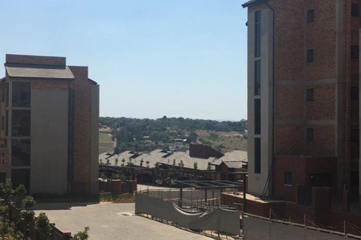 View of the apartment complex exterior featuring brick facades, paved driveway, and surrounding landscape.