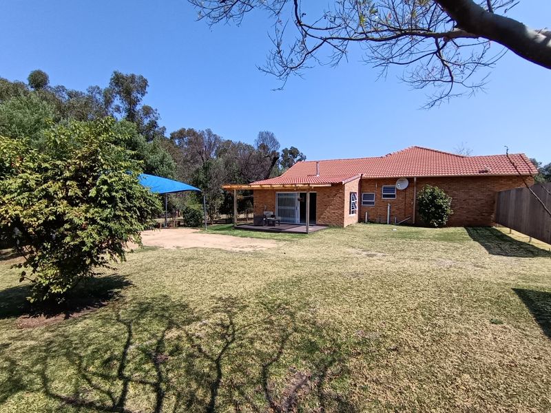 Rear view of the property featuring a facebrick facade, terracotta tiled roof, and a timber pergola leading to the garden area.