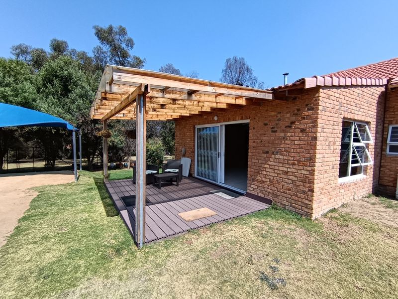 A rear patio featuring a timber pergola structure and composite decking, providing direct access to the interior through sliding glass doors.
