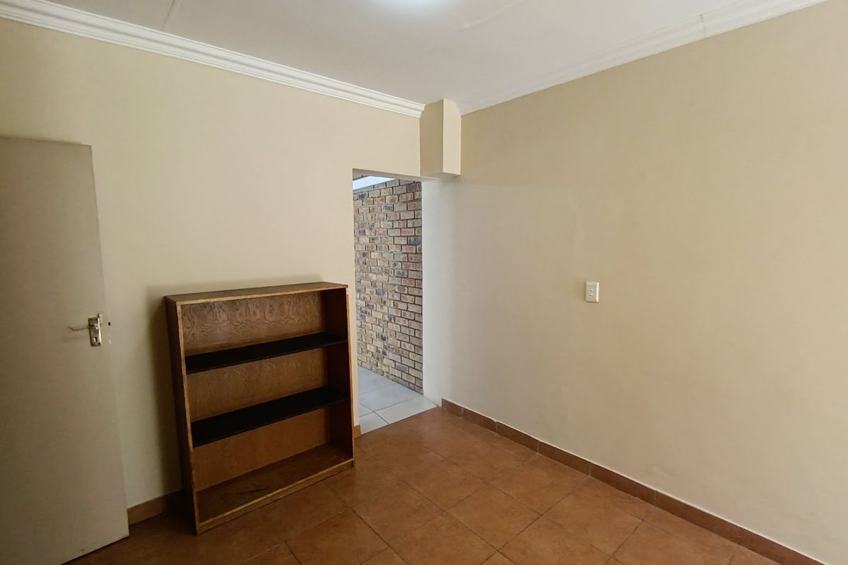A simple, vacant bedroom featuring tiled flooring and neutral wall finishes, providing a blank canvas for personalization.