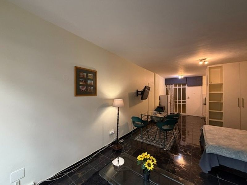 An open-plan living area featuring dark tiled flooring, built-in shelving, and a glass-paneled door leading to an exterior space.