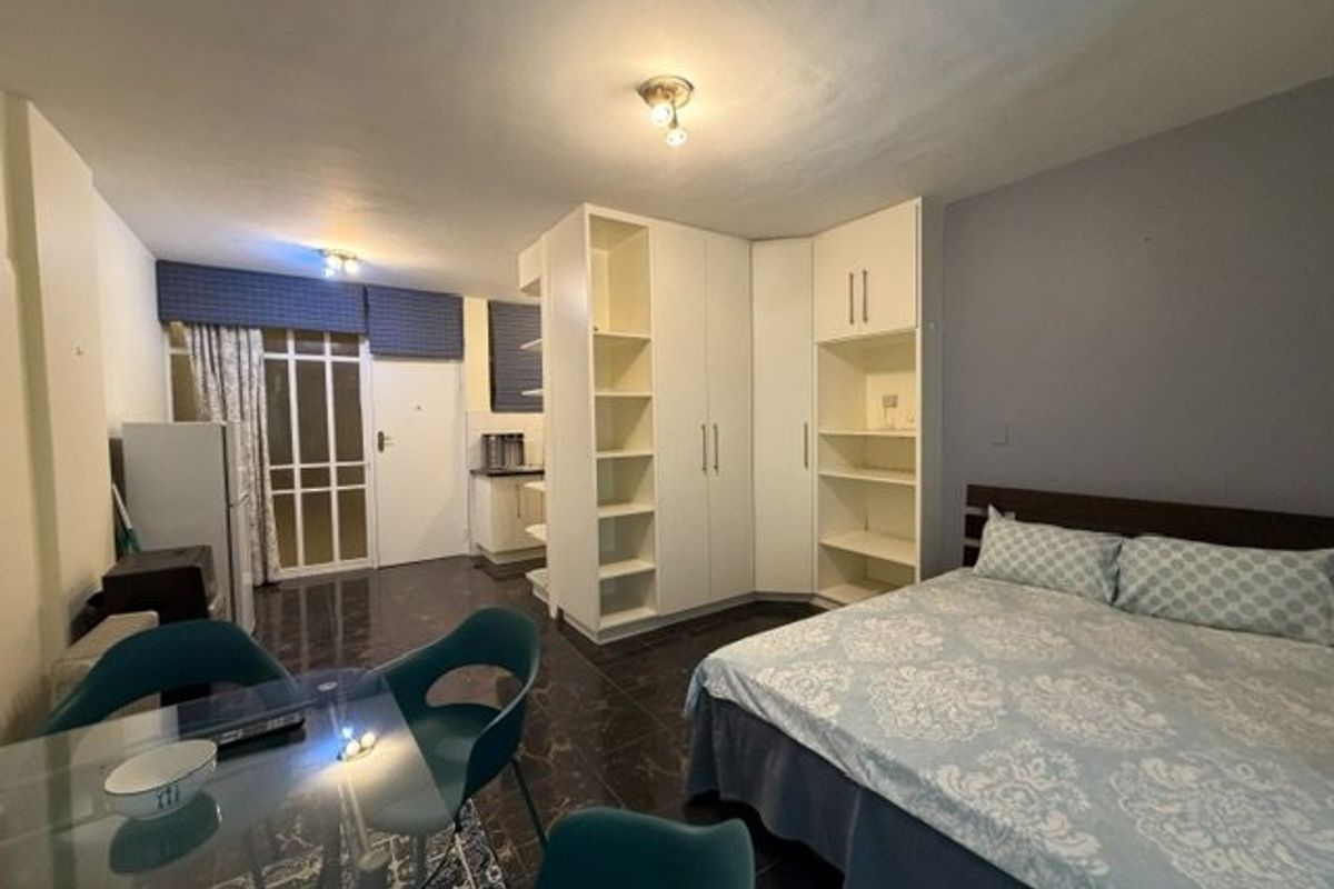 Open-plan studio apartment featuring tiled flooring, built-in storage cupboards, and direct access to an exterior entrance.