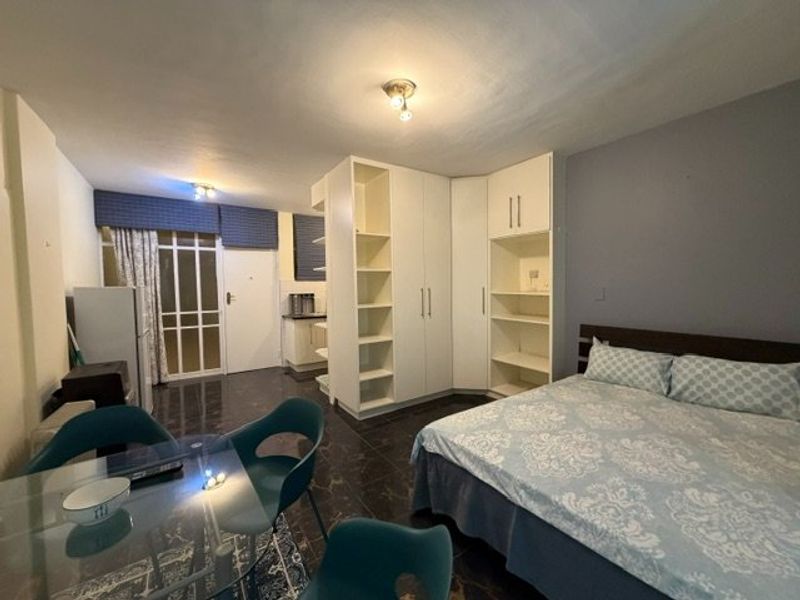 Open-plan studio apartment featuring tiled flooring, built-in storage cupboards, and direct access to an exterior entrance.