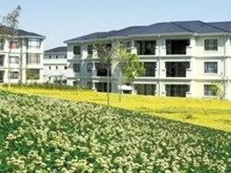 A view of a multi-story townhouse complex featuring landscaped garden areas and private balconies.