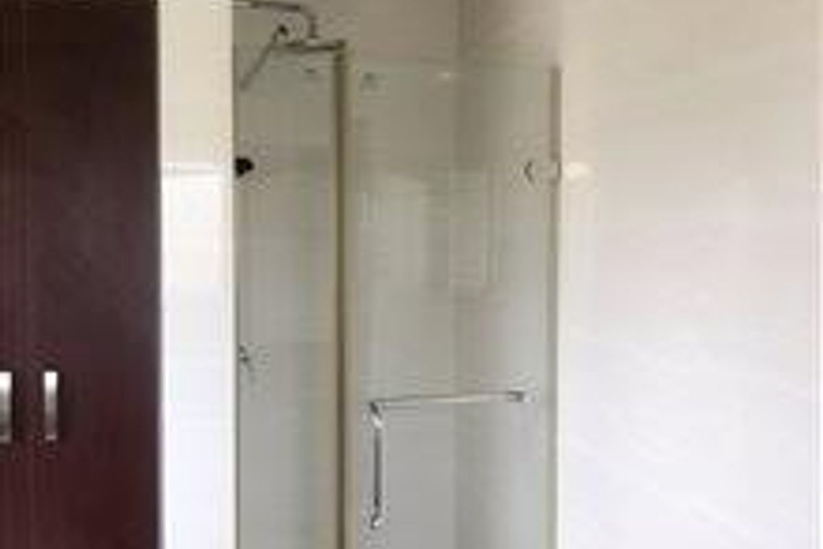 A modern bathroom featuring a glass-enclosed shower with tiled walls and built-in cabinetry.