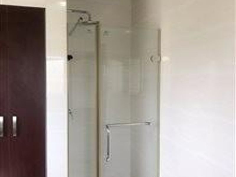 A modern bathroom featuring a glass-enclosed shower with tiled walls and built-in cabinetry.
