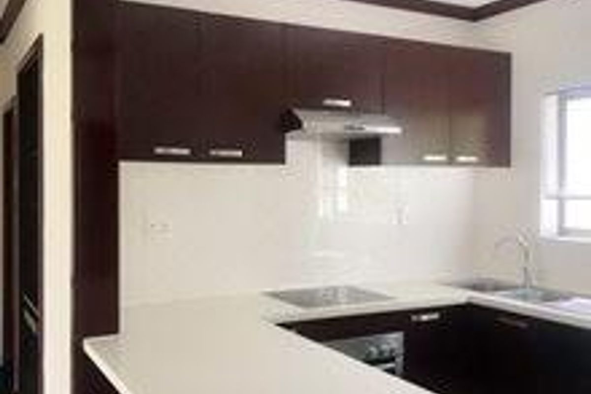 A modern kitchen featuring dark wood cabinetry, white stone countertops, a built-in oven, and a stainless steel extractor fan.
