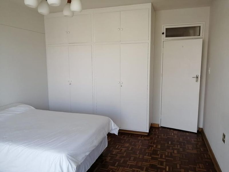 Bedroom featuring classic parquet flooring and extensive floor-to-ceiling built-in cupboards providing ample storage space.
